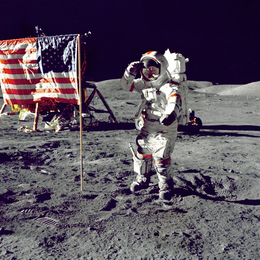 Un astronauta NASA sulla luna di fianco alla bandiera USA.