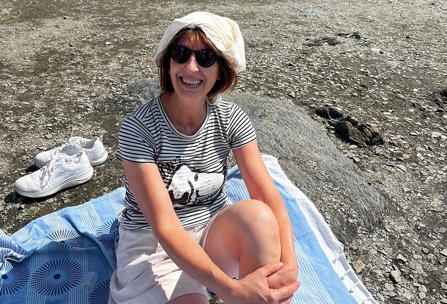 Paola Barberis lächelt mit Sonnenbrille und einem T-Shirt, das sie sich wie einen Turban um den Kopf gewickelt hat.